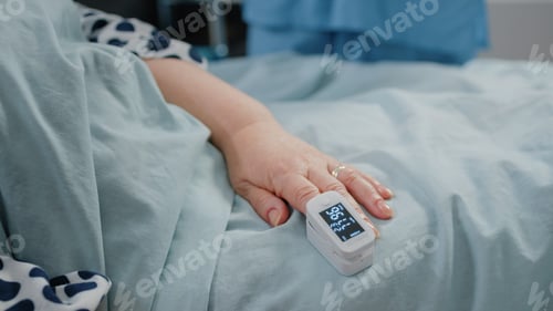 Preview: Close up of oximeter on hand of senior patient laying in bed