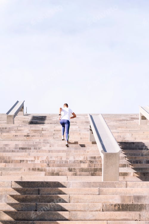 Vorschau: Rückansicht einer Sportlerin, die auf einer Treppe trainiert