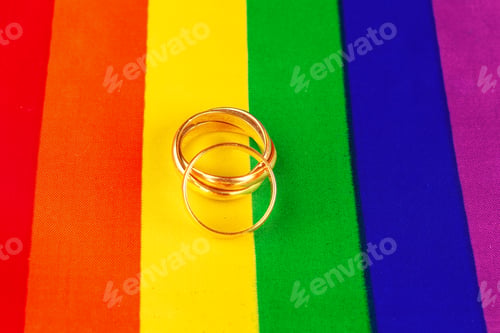 Preview: Two gold wedding rings on rainbow lgbt flag