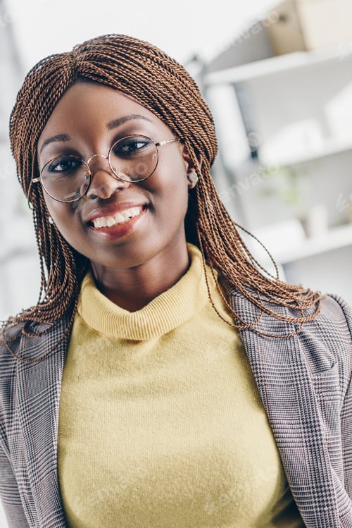 Preview: portrait of smiling stylish african american adult businesswoman in formar wear and round glasses