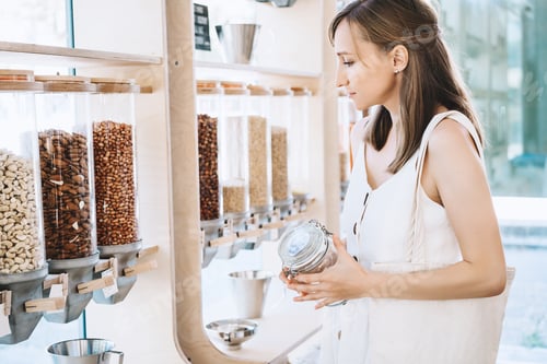 Preview: Zero waste shop. Girl buying in sustainable plastic free grocery store.