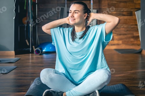 Preview: Young woman sitting on a mat in a fitness center, doing yoga and stretching.