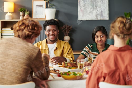 Preview: Multiethnic Young Adults Enjoying Thanksgiving Dinner Gathering at Home Table