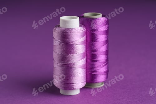 Preview: Spools of sewing threads on violet background, closeup