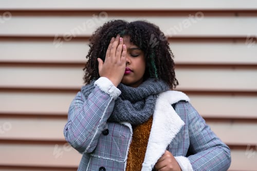 Preview: Black ethnic woman making a stop racism gesture on a gray wall, covering her eyes