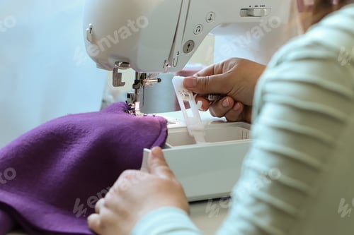 Preview: A woman sews children's clothes on a sewing machine. Hands of a seamstress. seamstress profession