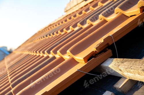 Preview: Closeup of metal montage anchor for installation of yellow ceramic roofing tiles mounted on wooden