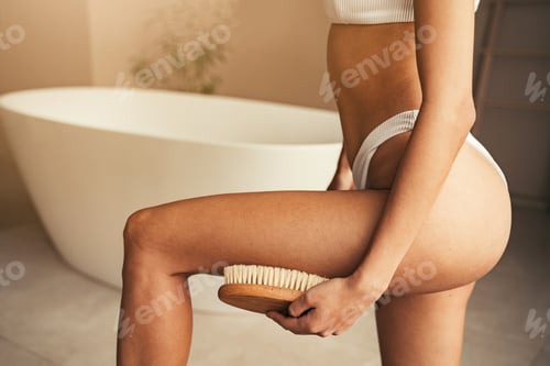 Preview: Close-up of woman massaging legs, dry brushing with wooden brush in the bathroom