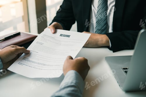 Preview: Asian young adult sitting at desk across from manager