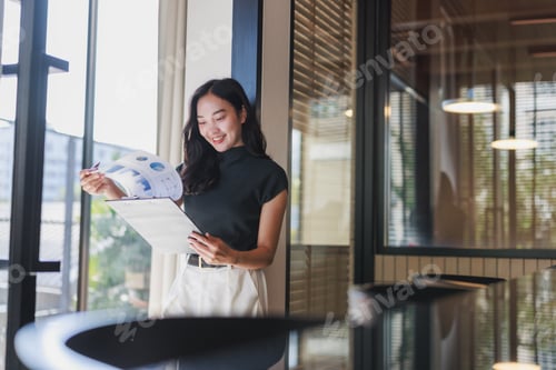 Preview: Young asian businesswoman analyzing financial data in modern office