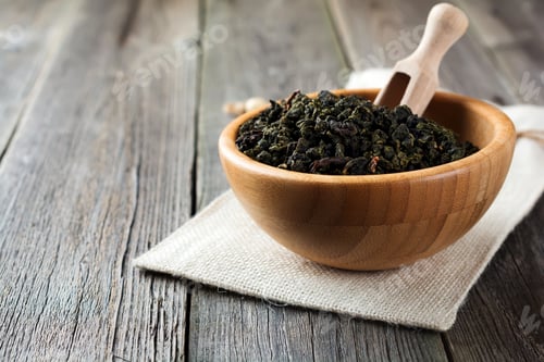 Preview: Oolong green tea in white bamboo bowl on a wooden table. Selective focus