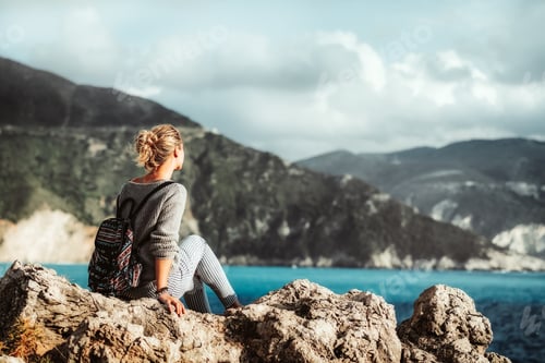 Preview: Female siting on rocky shore enjoying sea and coastline of Kefalonia island, Greece