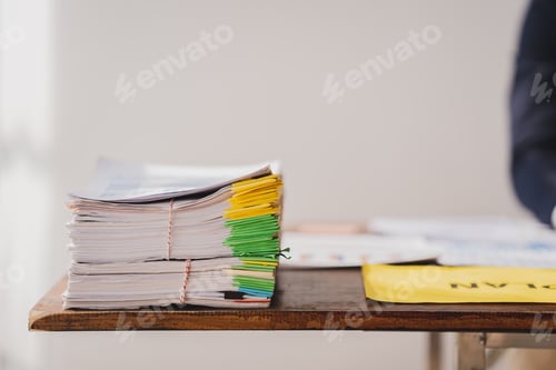 Preview: work from office A businessman works a bunch of paper files to find information on his desk at home.