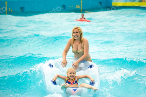 Preview: a woman with a child in a rubber inflatable circle plays in the pool of a summer water park in the