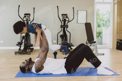 Preview: happy black healthy father lying enjoy playing lift excited little child son in fitnees sport happin