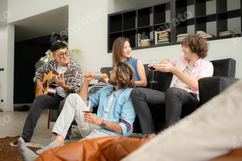 Preview: Multiethnic group of friends having fun playing guitar and singing together at home