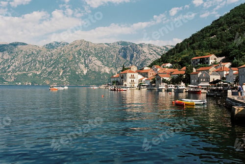 Preview: Boats moored at the pier of Perast with old houses at the foot of the mountains