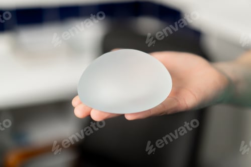 Preview: close-up in a plastic surgery clinic a doctor holds one implant in his hand