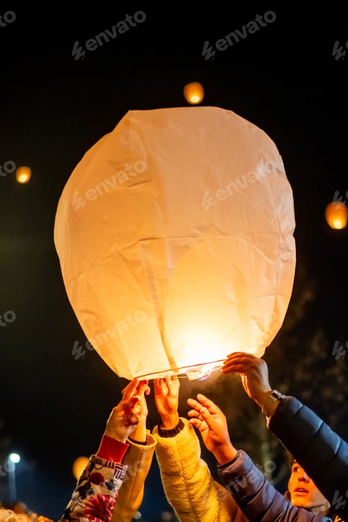 Preview: Group releasing glowing lantern during nighttime celebration