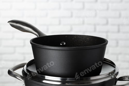 Preview: Set of cookware on table against white brick wall