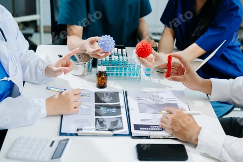 Preview: Medical team having a meeting with doctors in white lab coats and surgical scrubs seated at a table