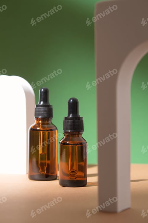 Preview: Beauty collagen face serum in a glass dropper bottles in Arch on green background. Trendy shoot of
