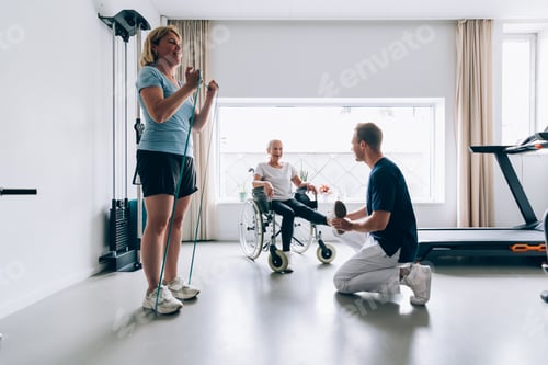 Preview: two patients in gym clinic doing rehab exercises with physiotherapist