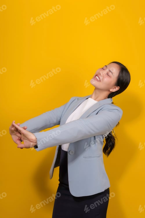 Preview: Young businesswoman is stretching her arms with her eyes closed, enjoying a moment of relaxation