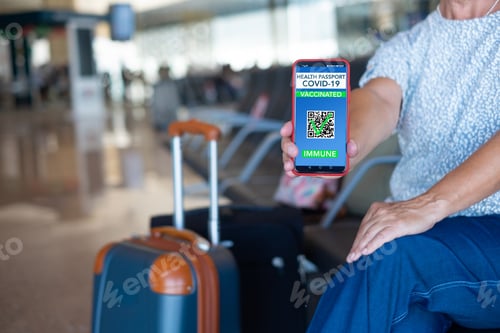 Preview: Senior traveler in airport showing green pass vaccination passport on mobile phone