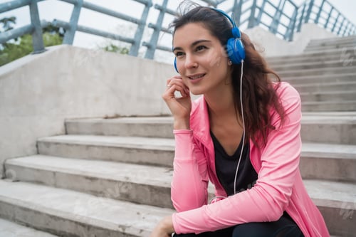 Preview: Athletic woman listening to music on a break from training.