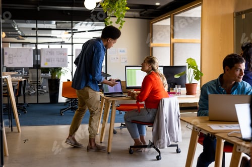 Preview: Diverse male and female colleagues in discussion using laptop in office