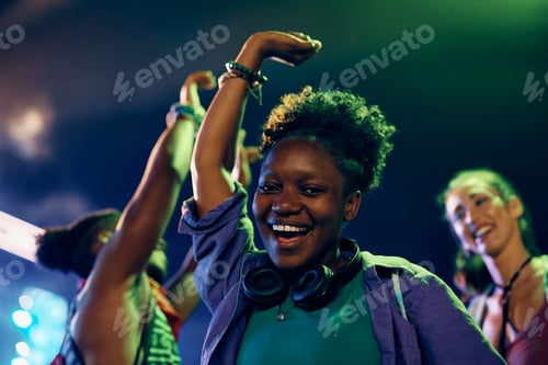 Preview: Happy black woman having fun and dancing on open air music concert at night.