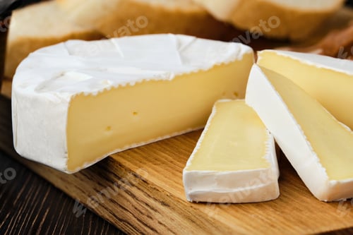 Preview: Close up of camembert or brie cheese on wooden cutting board
