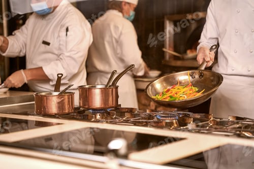 Preview: Cook frying vegetables on a pan in kitchen