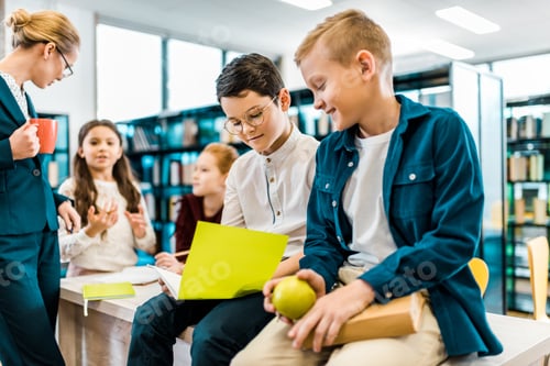 Visualização: adoráveis estudantes lendo livro na biblioteca
