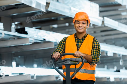Preview: smiling indian warehouse worker standing near pallet jack, smiling and looking at camera