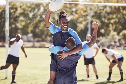 Preview: Diverse rugby teammates celebrating scoring a try or winning a match outside on a sports field. Rug