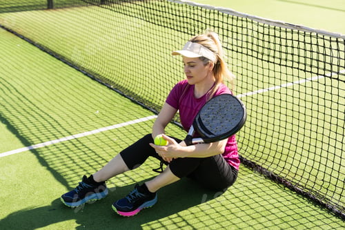 Preview: Happy female paddle tennis player during practice on outdoor court looking at camera. Copy space.