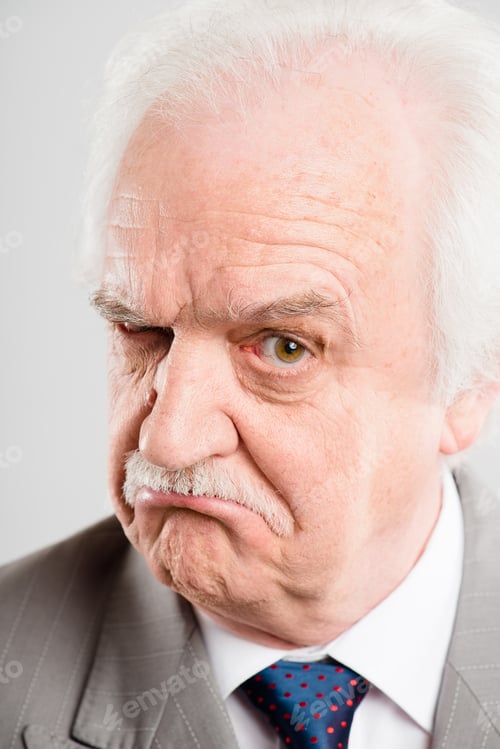 Preview: Ive got my eye on you. Shot of a senior man standing alone in the studio and looking skeptical.
