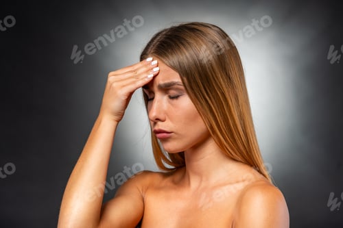 Preview: Woman Experiencing a Headache in Front of Gray Background