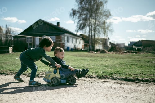 Preview: The boy rides his younger brother's toy car. Summer in the village