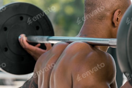 Preview: cropped shot of muscular african american sportsman lifting barbell in gym