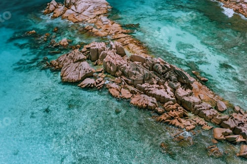 Preview: Aerial top view of granite rock formation surrounded by blue ocean lagoon. La Digue, Seychelles
