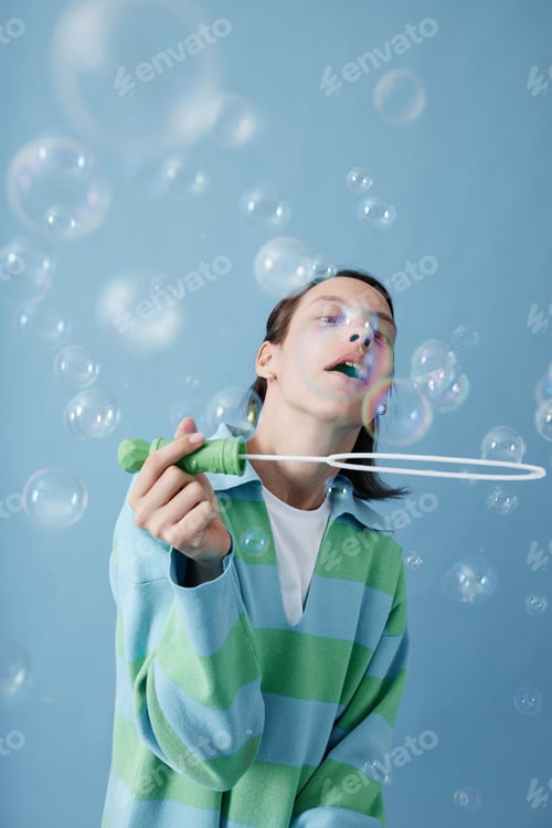 Preview: Girl with cerebral palsy blowing bubbles against blue background