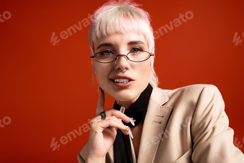 Preview: Young woman with stylish glasses and a confident smile posing against a vibrant orange background