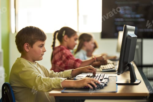 Preview: Caucasian Boy Using Computer in Classroom with Diverse Children Learning Coding