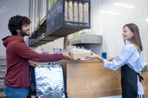 Preview: Curly-haired young courrier taking meal box for delivery