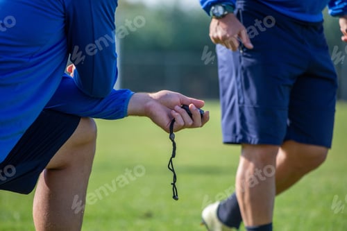 Preview: Kneeling coach with chronometer, stopwatch in hand trains an athlete on blur stadium background.