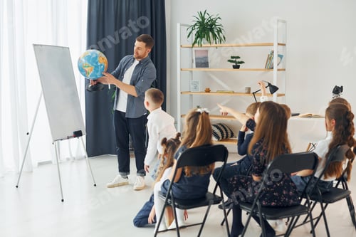 Preview: Teaching geography lesson by using Earth globe. Group of children students in class