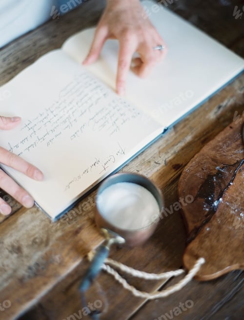 Preview: A woman in a domestic kitchen, reading a recipe book.